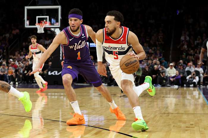 Washington Wizards guard Tyus Jones (5) drives to the net against Phoenix Suns guard Devin Booker (1) during the first quarter at Footprint Center.